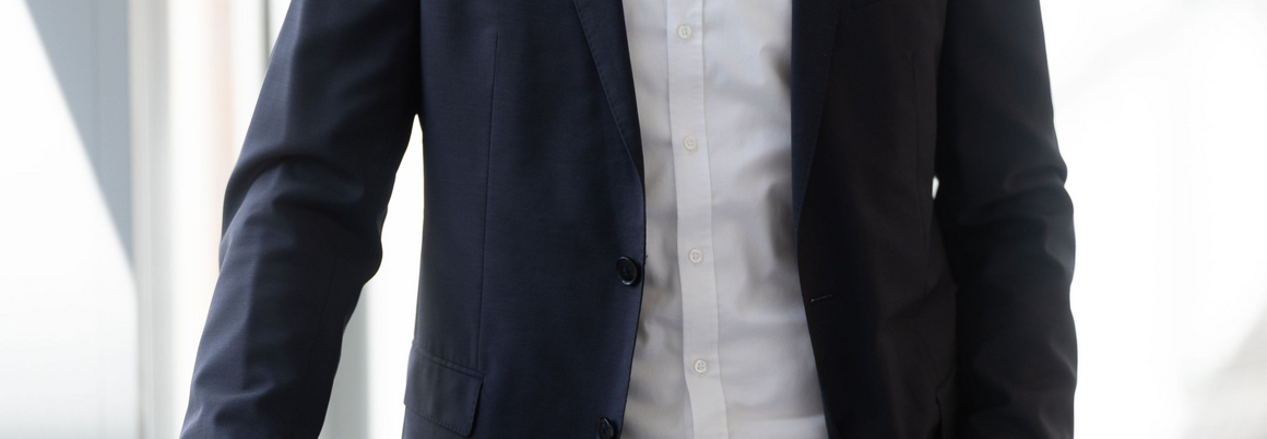 Lächelnder Mensch im Anzug in einem hellen Flur.